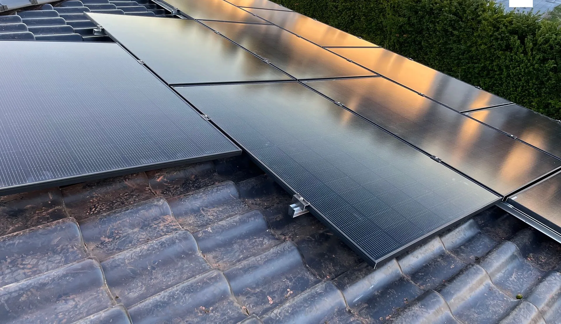 Close view of solar panels mounted on a concrete tiled roof in evening light